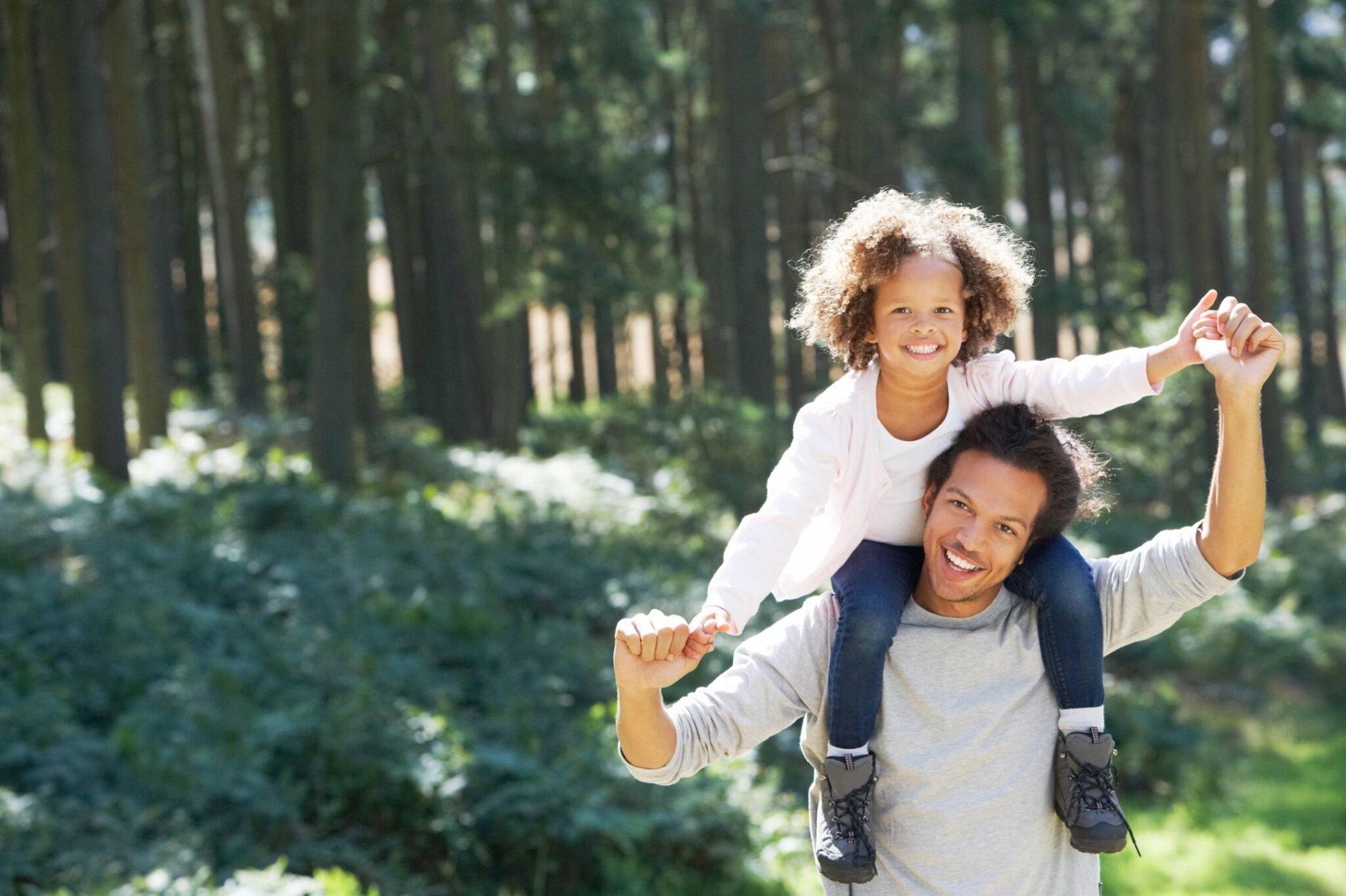 Dad with daughter on his shoulders walking in the woods in nature